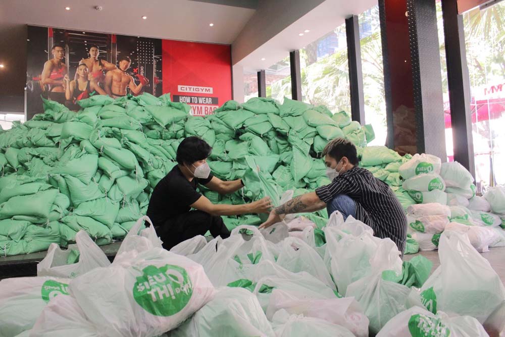 Zino và nhạc sĩ Nguyễn Văn Chung (phải) hỗ trợ nhau chia gạo vào từng túi. Họ và nhóm thanh niên khỏe mạnh chịu trách nhiệm vác gạo ra xe