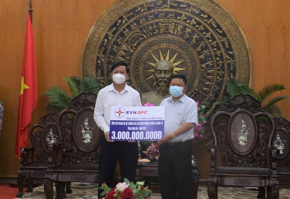 Ông Nguyễn Văn Út, Chủ tịch UBND tỉnh Long An (phải) tiếp nhận nguồn kinh phí 3 tỉ đồng hỗ trợ công tác phòng chống dịch do đại diện Công ty Điện lực Long An thay mặt EVNSPC trao