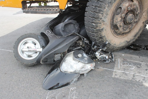 Một xe gắn máy của người đi đường đang đậu đèn đỏ bị xe cẩu gây tai nạn cán bẹp