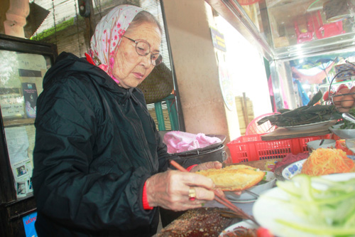 “Madam Khanh” cẩn thận bỏ nhân vào bánh mì bán cho khách - Ảnh: Hoàng Sơn