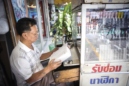 Thầy Lê Văn Sợt, sinh tại Thái Lan, thường lấy từ điển tiếng Việt ra tự học khi tiệm vắng khách - Ảnh: Nguyễn Tập 