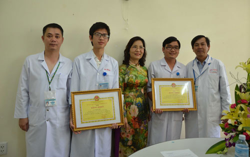 Đại diện lãnh đạo Sở Y tế trao bằng khen cho 2 bác sĩ Hiệu và Tuyên (cầm bằng khen)