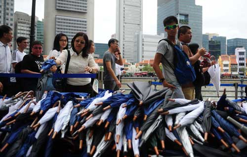 Người dân Singapore trả lại dù miễn phí, vốn được chính quyền bố trí cho những người xếp hàng chờ vào viếng ông Lý Quang Diệu - Ảnh: AFP