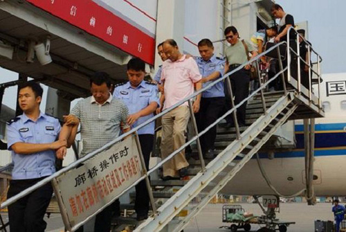  Hai nghi phạm kinh tế (thứ 2 và thứ 4 từ trái sang) bị đưa về Trung Quốc hồi tháng 8.2014 sau khi trốn sang Campuchia cùng tài sản phi pháp - Ảnh: China Daily