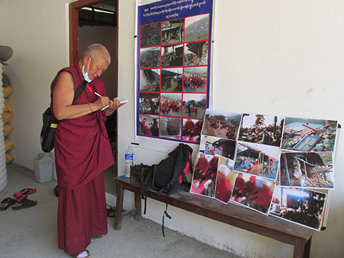 Ni sư trưởng Ngawang Dechen bên những hình ảnh các ni bị thương và cảnh đổ nát ở Singdak Gompa