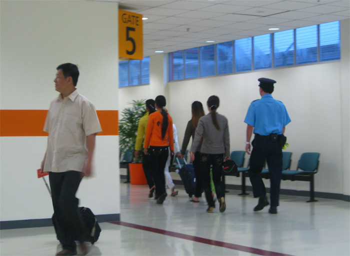 An ninh sân bay Changi áp giải các cô gái Việt bị từ chối nhập cảnh ra máy bay hãng Tiger Airways để về nước - Ảnh: Thục Minh
