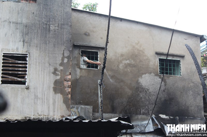Một người dân nhà cạnh bên cũng dùng vòi nước  để chữa cháy - Ảnh: Phạm Hữu