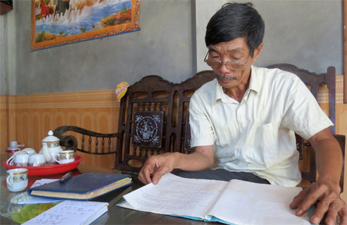 Ông Huỳnh Văn An, Trưởng thôn Bình Lộc đọc bản quy ước của làng quy định nữ từ 20 tuổi, nam từ 22 tuổi mới được kết hôn - Ảnh: Tuyết Khoa