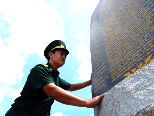 Đại úy Ngô Xuân Kiên, Chính trị viên phó Đồn BP Phước Tân bên bia ghi danh các liệt sĩ của đồn - Ảnh: MTH