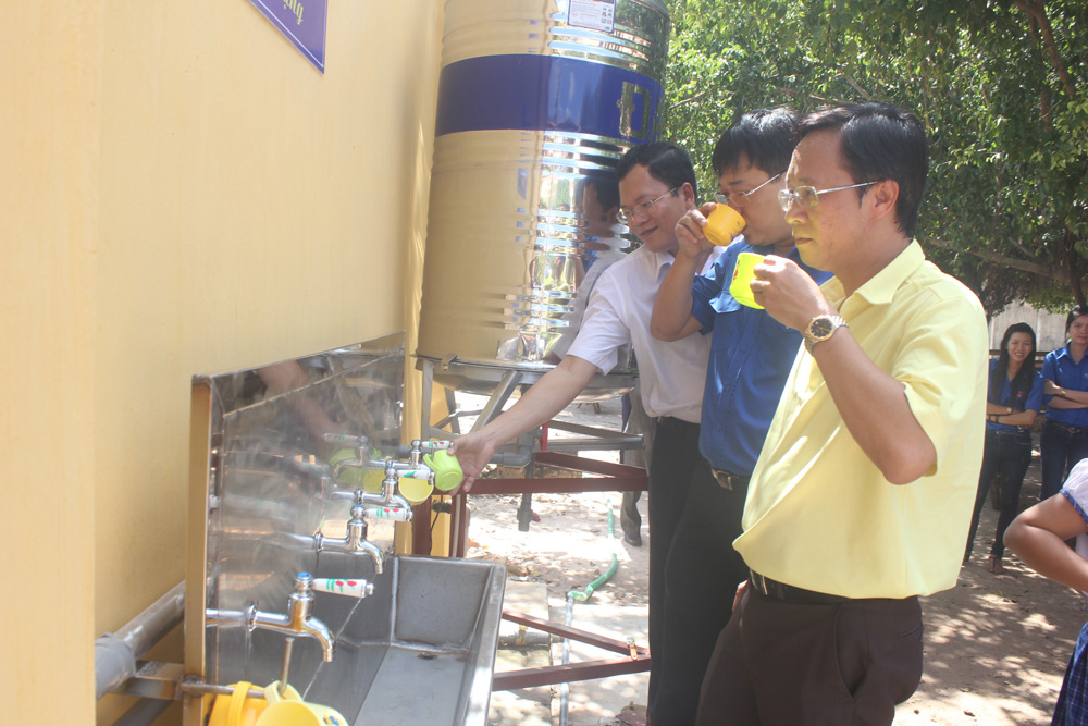 Anh Lê Quốc Phong (giữa) cùng Bí thư tỉnh Đoàn và lãnh đạo công ty sử dụng nước lọc tại trường Tiểu học Phước Vinh - Ảnh: Giang Phương