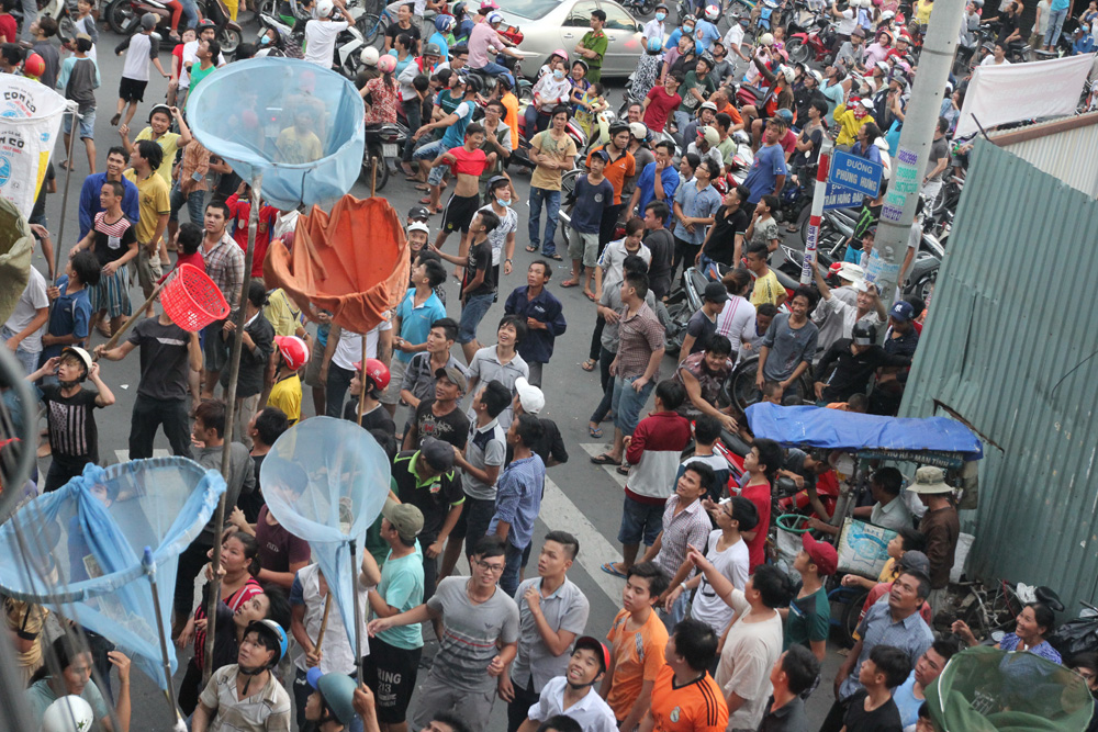 Nhiều người tranh nhau giật đồ cúng cô hồn tại góc đường Phùng Hưng - Trần Hưng Đạo (Q.5) chiều 28.8 gây náo loạn cả khu vực - Ảnh: Mã Phong