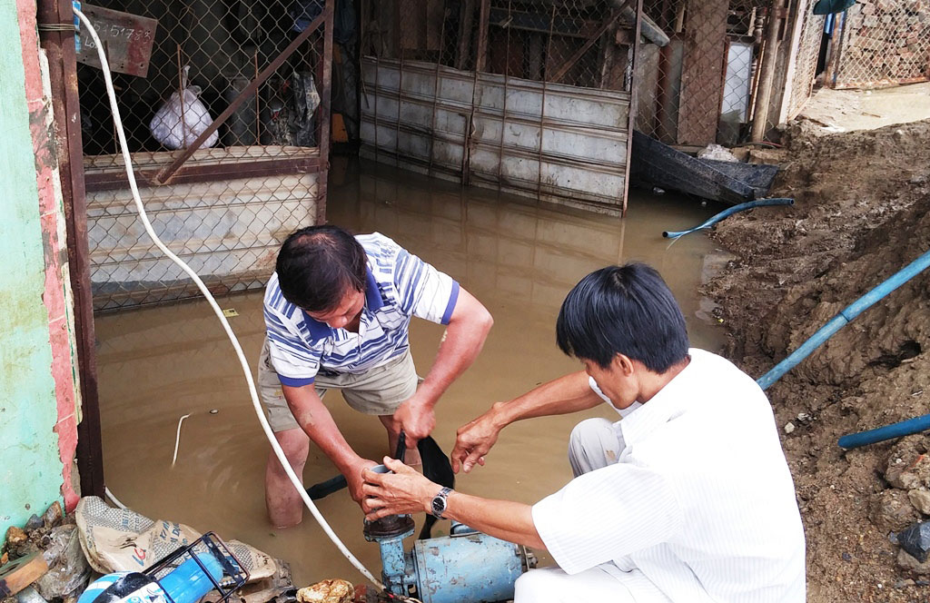 Người dân bơm nước từ trong nhà ra đường -  Ảnh: Nguyễn Chung