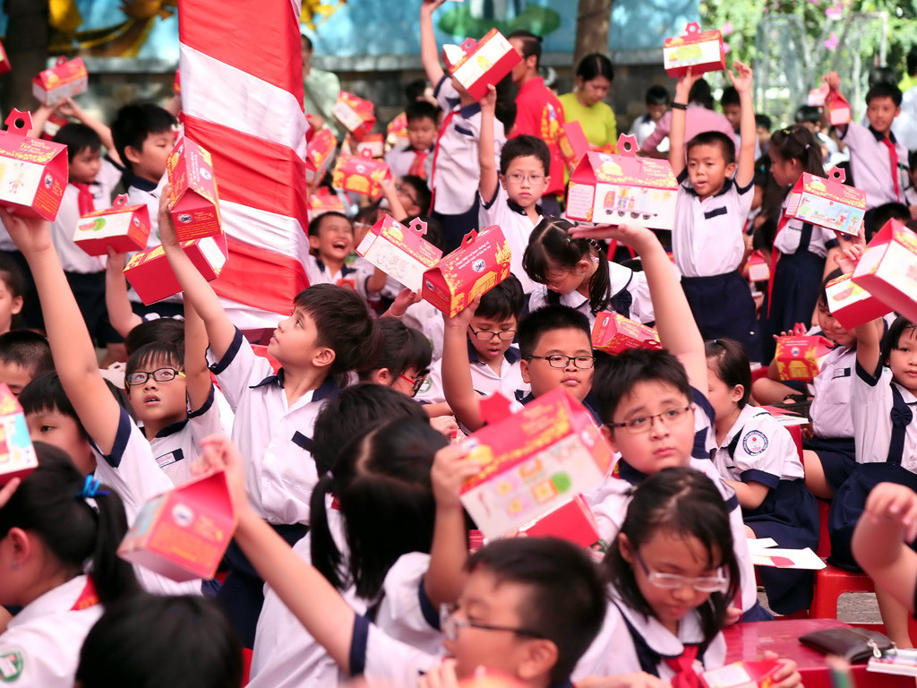 Học sinh giơ cao những hộp quà để tặng các gia đình xa quê trên hành trình đoàn tụ - Ảnh: Đào Ngọc Thạch