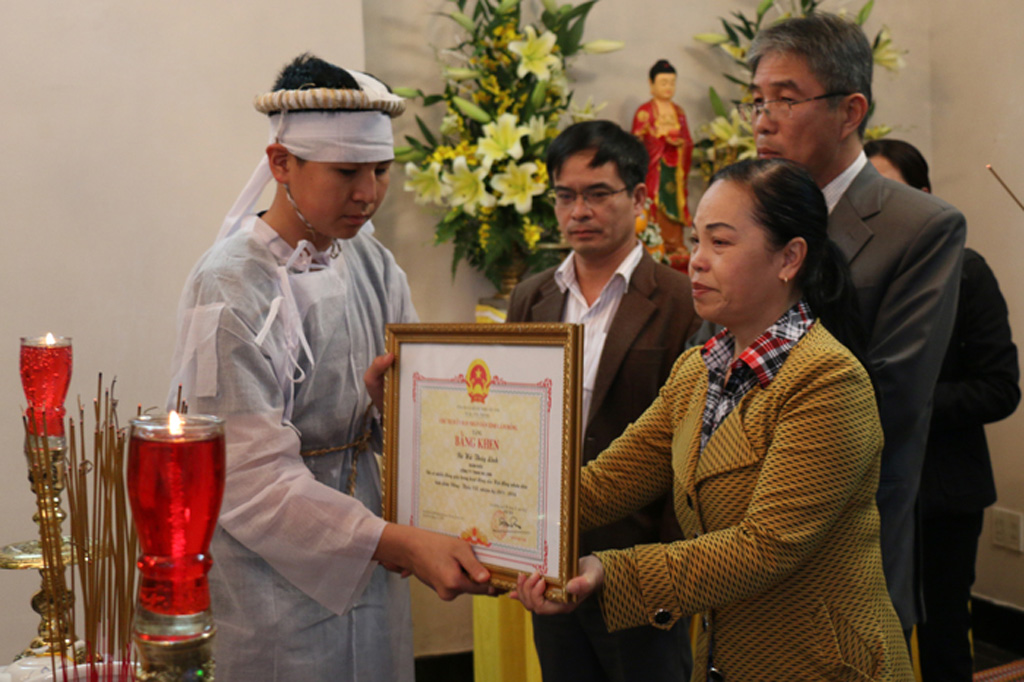 Bà Hoàng Thị Thu Hồng trao bằng khen của UBND tỉnh cho con trai bà Hà Linh - Ảnh: Lâm Viên
