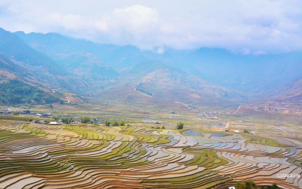 Những thửa ruộng loang loáng nước trải dài dưới chân những ngọn núi cao xanh tím, bên trên là mây trắng vờn quanh