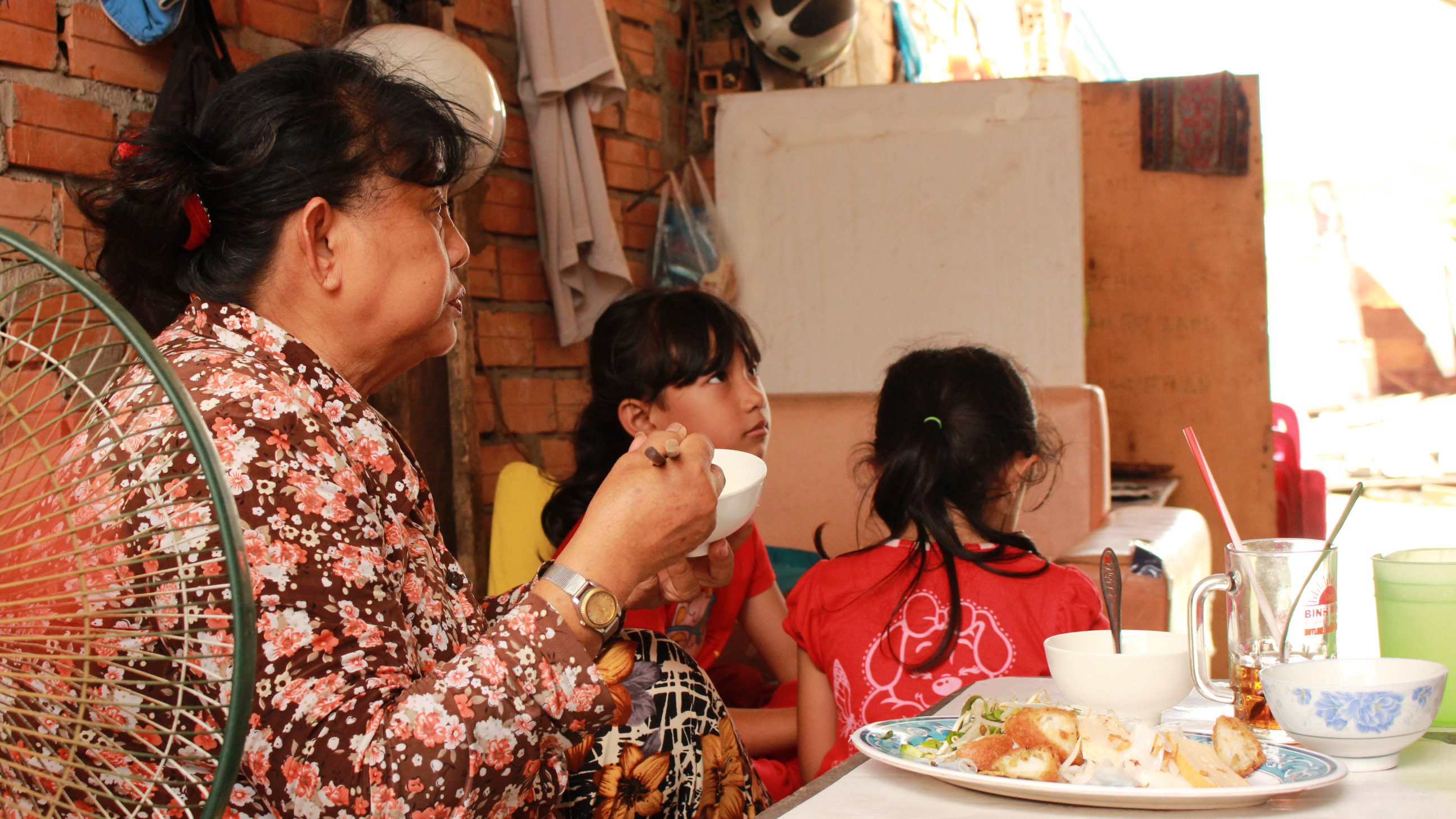 Bà Nguyễn Thị Phúc (đường Trần Xuân Soạn, quận 7) và các cháu đang ăn trưa. Vì nhà quá hẹp không đủ chỗ ngồi nên ăn cơm cũng phải "chia ca"